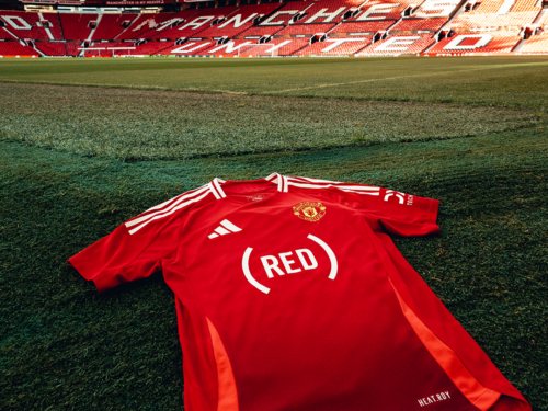 (RED)'s logo on Manchester United's Jersey laid out on a soccer pitch